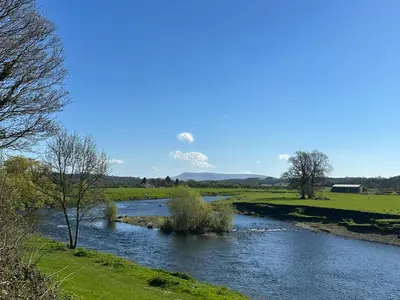 a river in a field next to a field with trees at Ribble Valley Cottage in Preston