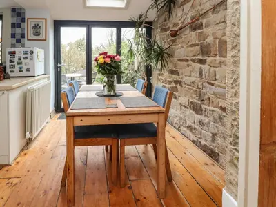 a dining room table with chairs and a stone wall at Ribble Valley Cottage in Preston