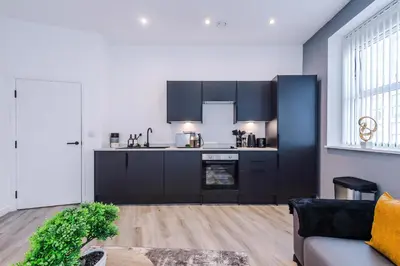 a kitchen with black cabinets and a living room at The Seven Suites Liverpool in Liverpool