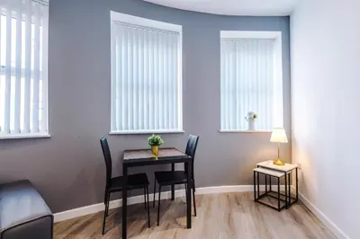 a dining room with a table and chairs and windows at The Seven Suites Liverpool in Liverpool