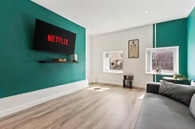 a living room with a couch and a green wall at The Seven Suites Liverpool in Liverpool