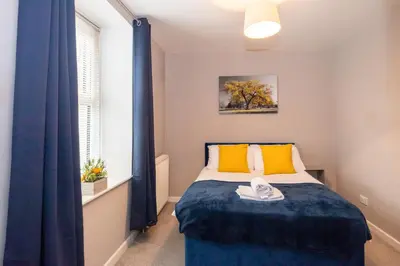 a bedroom with a bed with yellow pillows and a window at Church Street Cottage Great Harwood in Great Harwood