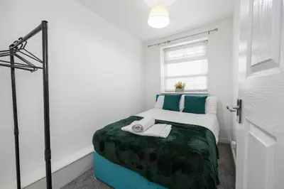 a bedroom with a bed with green sheets and a window at Church Street Cottage Great Harwood in Great Harwood