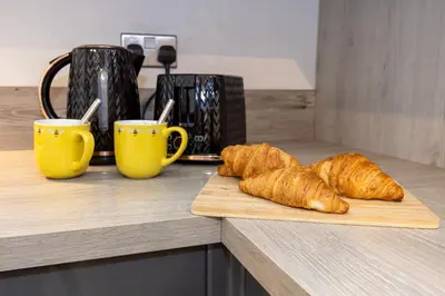 two croissants on a cutting board next to two cups at Church Street Cottage Great Harwood in Great Harwood