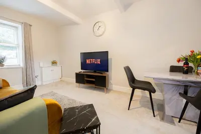 a living room with a television and a desk with a chair at Church Street Cottage Great Harwood in Great Harwood