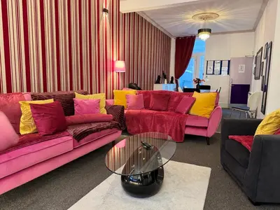 a living room with pink and yellow couches and a table at Winter Gardens large modern home in Blackpool