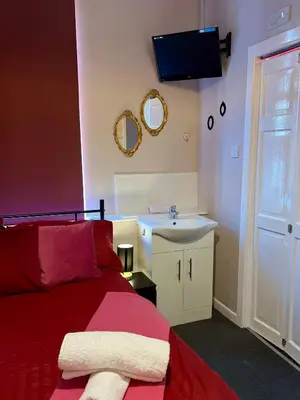 a bedroom with a red bed and a sink at Winter Gardens large modern home in Blackpool