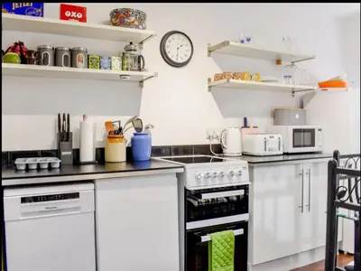 a kitchen with white appliances and a clock on the wall at Buxton Mews in Ulverston