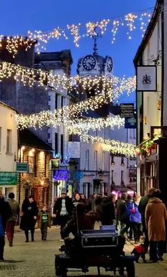 a crowd of people walking down a street with christmas lights at Buxton Mews in Ulverston