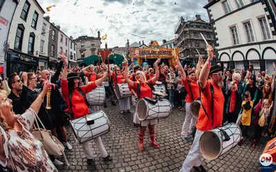 a group of people playing drums in a parade at Buxton Mews in Ulverston