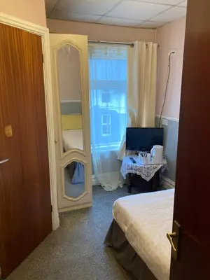 a room with a bedroom with a bed and a mirror at Iona Hotel in Blackpool