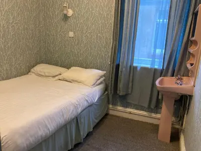 a small bedroom with a bed and a sink at Iona Hotel in Blackpool