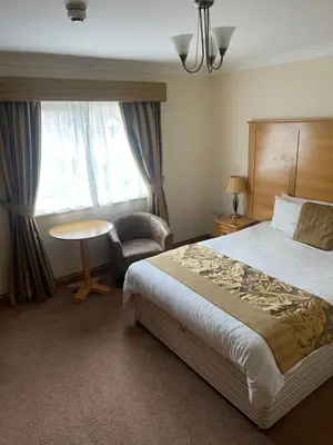 a hotel room with a bed and a chair and a window at The Chetwynde - Self Check In HMO in Barrow in Furness