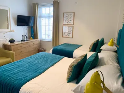 a bedroom with two twin beds and a television at The Fylde International Guest House in Blackpool
