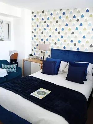 a bedroom with a large bed with a blue headboard at The Fylde International Guest House in Blackpool