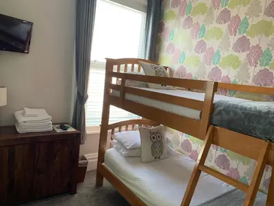 a bedroom with two bunk beds and a window at The Fylde International Guest House in Blackpool