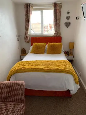 a bedroom with a bed with a yellow blanket and a window at The Fylde International Guest House in Blackpool