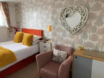 a bedroom with a bed and a mirror and a chair at The Fylde International Guest House in Blackpool