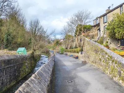 a road next to a stone wall and a canal at 40 The Gill - Ulverston Town Centre in Ulverston