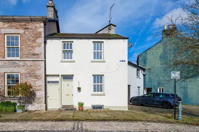 a white house with a car parked in front of it at 40 The Gill - Ulverston Town Centre in Ulverston