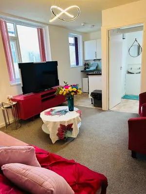 a living room with a tv and a table with flowers at Luminous Suites in Blackpool