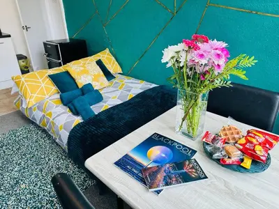 a bed with a vase of flowers on a table at Luminous Suites in Blackpool