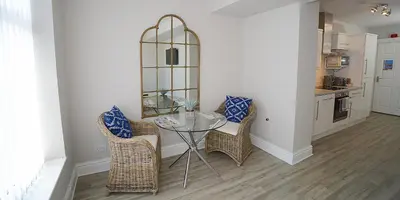 a dining room with a glass table and wicker chairs at Twelve Apartments in Blackpool