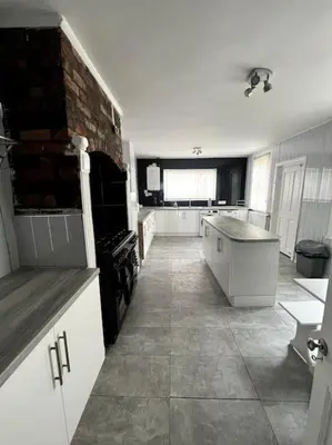 a large kitchen with white cabinets and a brick wall at No. 206 - Spacious 5 Bed in Liverpool