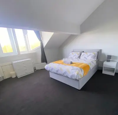 a white bedroom with a bed and two windows at No. 206 - Spacious 5 Bed in Liverpool