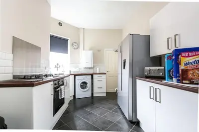 a kitchen with white cabinets and a washer and dryer at 5 bedroom house, free parking, near football, sleeps 8 in Liverpool