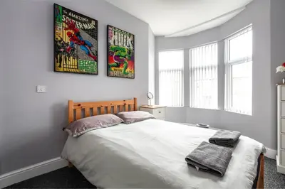 a bedroom with a bed with two posters on the wall at 5 bedroom house, free parking, near football, sleeps 8 in Liverpool