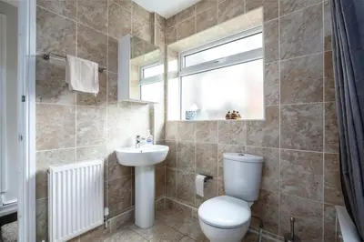 a bathroom with a toilet and a sink and a window at 5 bedroom house, free parking, near football, sleeps 8 in Liverpool