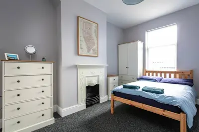 a bedroom with a bed and a dresser and a fireplace at 5 bedroom house, free parking, near football, sleeps 8 in Liverpool