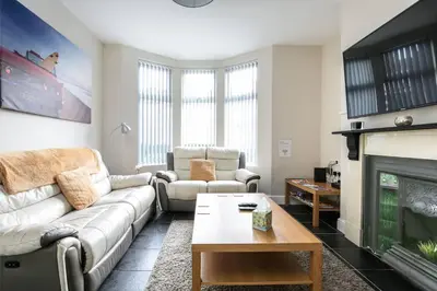 a living room with a couch and a fireplace at 5 bedroom house, free parking, near football, sleeps 8 in Liverpool