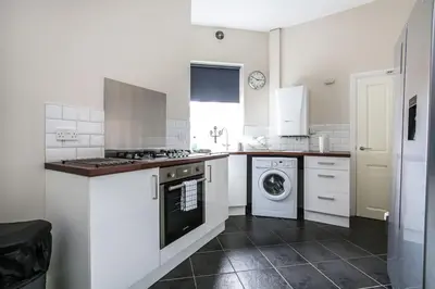 a white kitchen with a washer and dryer in it at 5 bedroom house, free parking, near football, sleeps 8 in Liverpool
