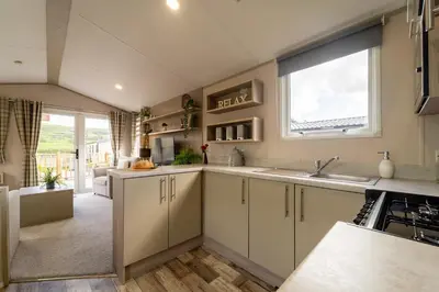a kitchen with white cabinets and a large window at Wiswell View Lodge: Pendle View Holiday Park in Clitheroe