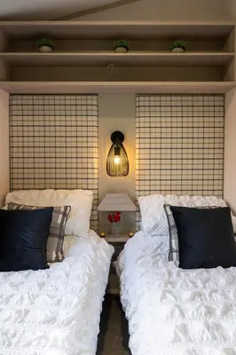 a bedroom with two beds with white sheets and a lamp at Wiswell View Lodge: Pendle View Holiday Park in Clitheroe