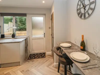 a kitchen with a table with chairs and a clock on the wall at 12 Merefell Road in Carnforth