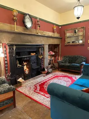 a living room with a fireplace and a red wall at Victorian Copper Cottage in Lancaster