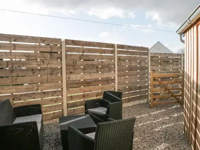 a patio with chairs and a wooden fence at Driftwood Studio in Ulverston