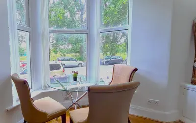 a glass table and chairs in a room with windows at Sidemersey Livings - Botanic Residence in Liverpool