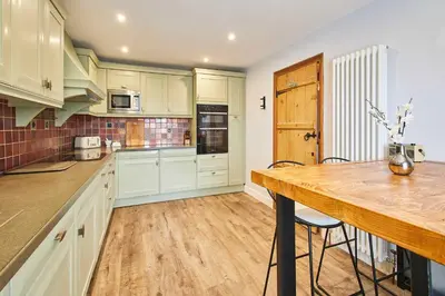 a kitchen with white cabinets and a wooden counter top at Host & Stay - Lime Tree House in Holme