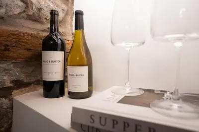 two bottles of wine sitting on a table with glasses at Wharton Cottage, Cartmel, Lake District Retreat - Ridgestone in Cartmel