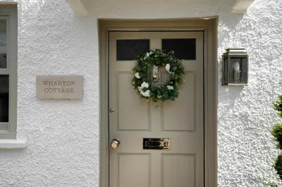 a door of a white building with a wreath on it at Wharton Cottage, Cartmel, Lake District Retreat - Ridgestone in Cartmel