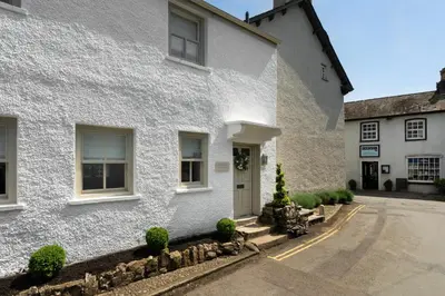 a white house with a street in front of it at Wharton Cottage, Cartmel, Lake District Retreat - Ridgestone in Cartmel