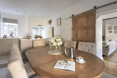a dining room table with a vase of flowers on it at Wharton Cottage, Cartmel, Lake District Retreat - Ridgestone in Cartmel