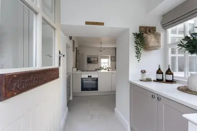 a kitchen with white cabinets and a counter with bottles of wine at Wharton Cottage, Cartmel, Lake District Retreat - Ridgestone in Cartmel