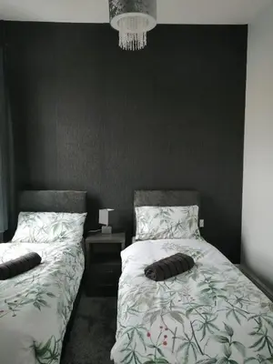 a bedroom with two beds and a black wall at Central Luxury Town House in Blackpool