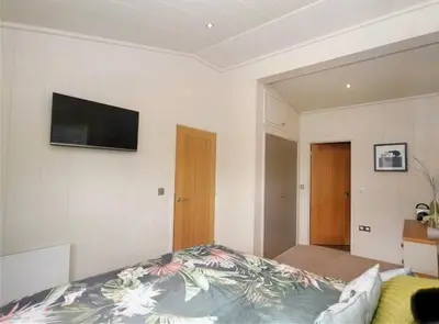 a bedroom with a bed and a flat screen tv at Tarka Halt 1 - Haven Lakeland Leisure in Flookburgh