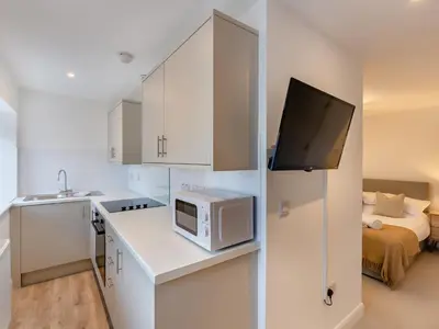 a small white kitchen with a microwave and a bed at Uk46867 - Thirlmere in Ulverston